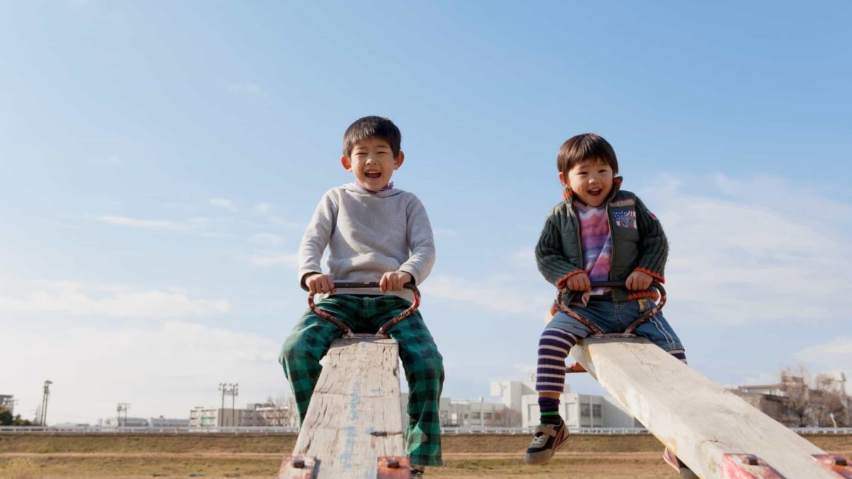 Two boys happy at the top of see saws.