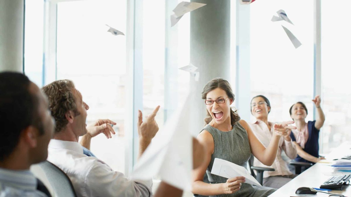 Businesspeople throwing paper airplanes in office.