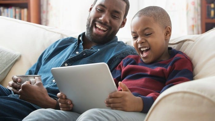 son playing game on iPad with dad watching netflix