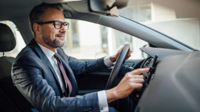 a man at the wheel of car with dashboard in view, driver technology shares,