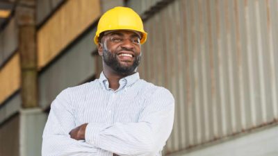 smiling engineer/ project manager in hard hat on site