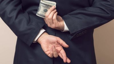 hiding money behind back with fingers crossed, tax evasion