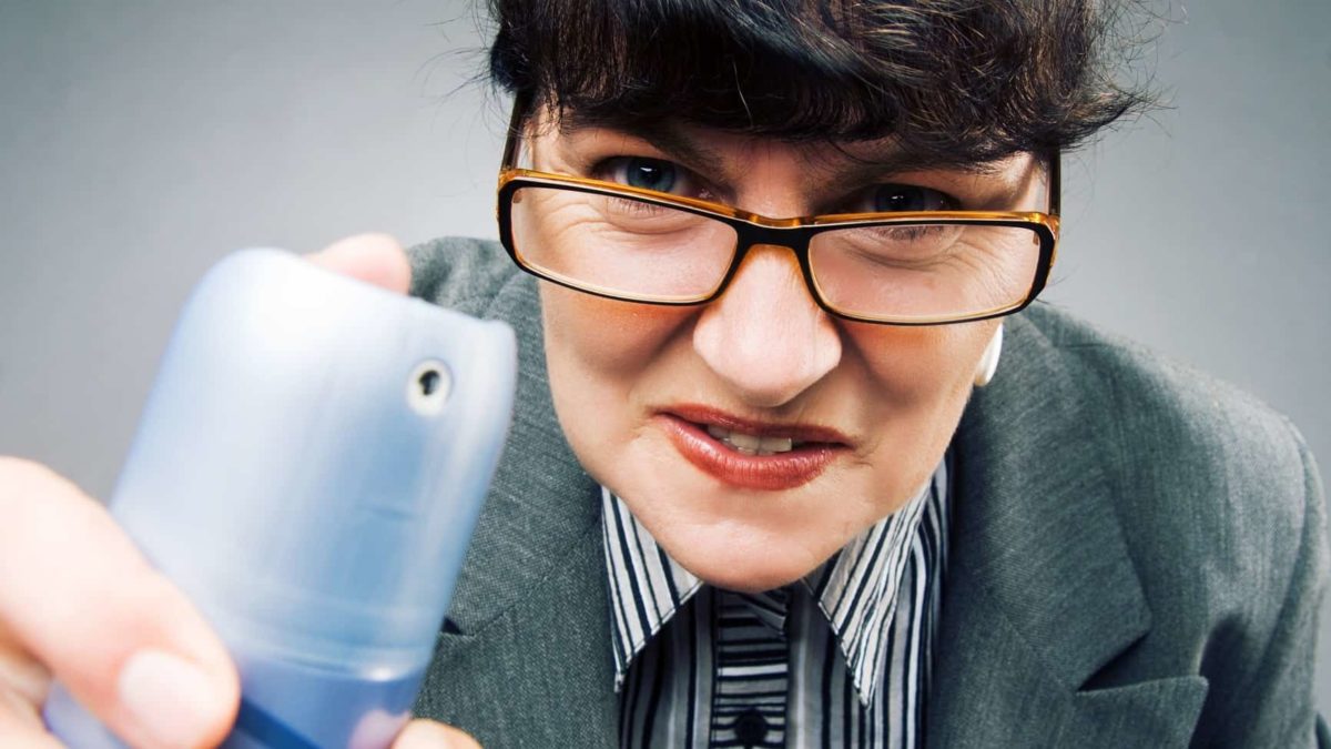 A woman wearing glasses peers closely at something, ready to spray antimicrobial treatment.