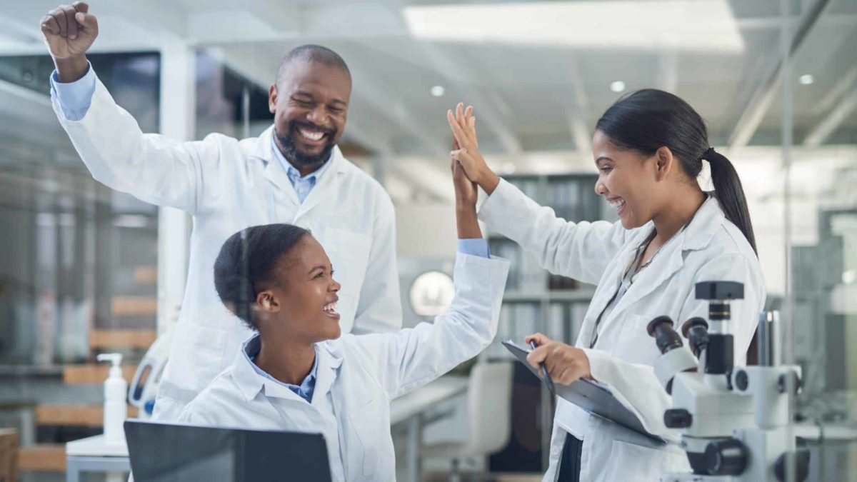 A group of science or medical professionals cheering good news in the lab.