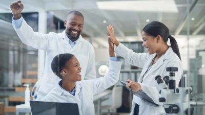 A group of science or medical professionals cheering good news in the lab.