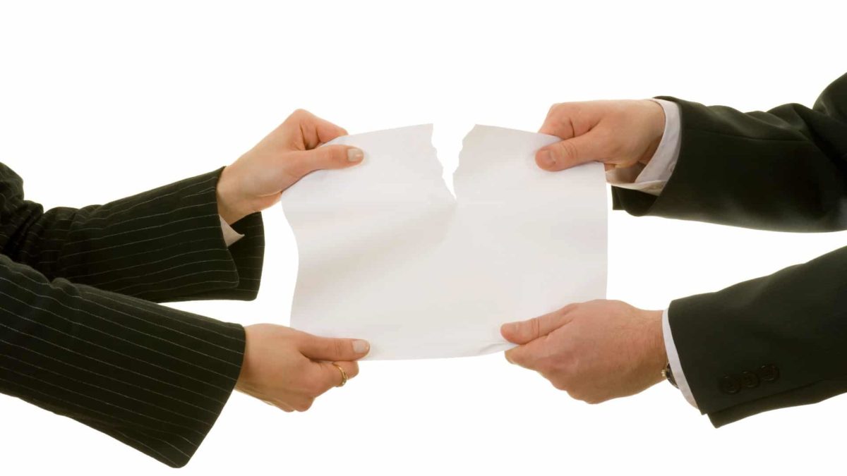 Two company executives split a piece of paer down the middle, indicating a company demerger