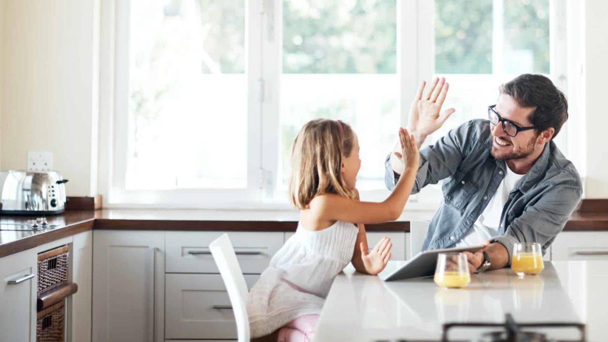 A high-five between father and daughter who are setting up an app on a laptop
