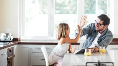 A high-five between father and daughter who are setting up an app on a laptop