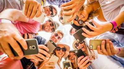 Group of friends trading stocks on their phones. symbolising the 3 most traded ASX 200 shares today
