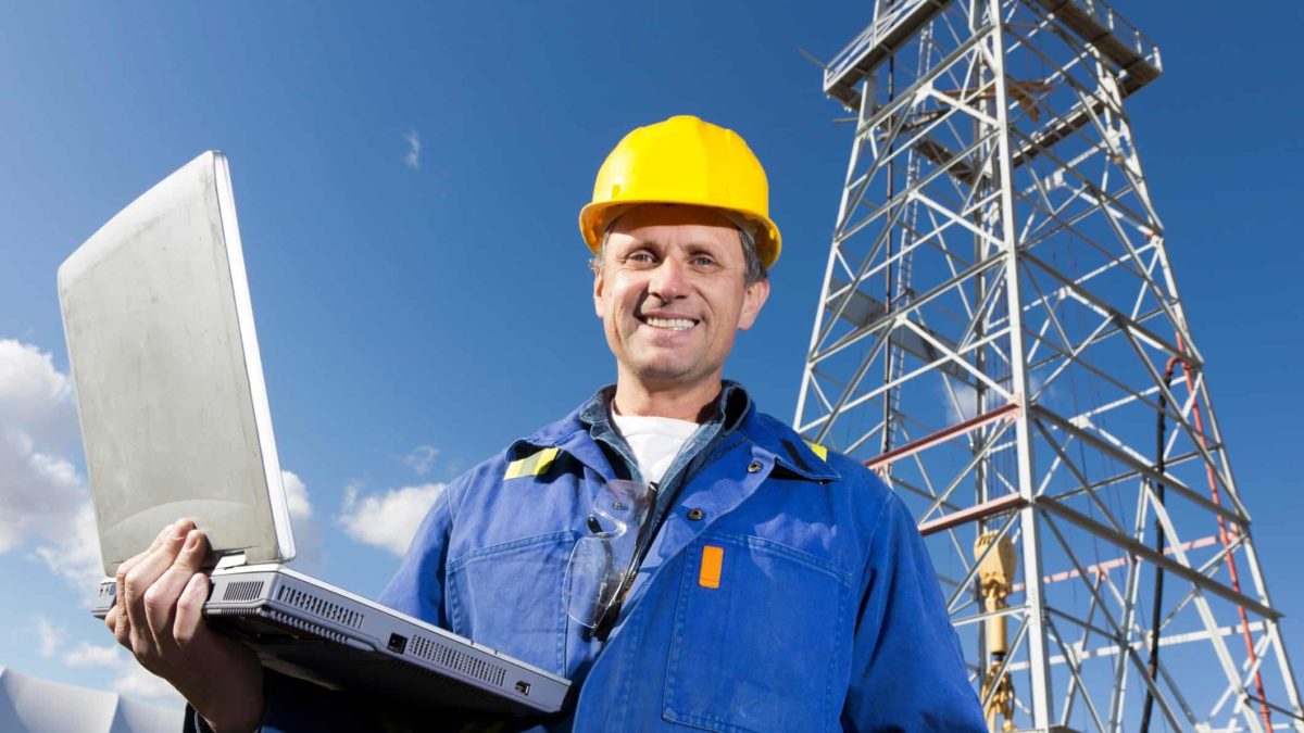 oil rig worker smiling with laptop