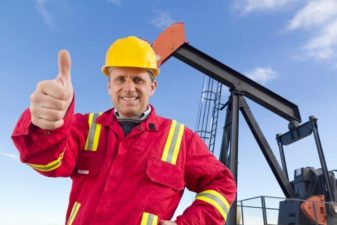 Santos share price worker in front of oil mine puts thumbs up