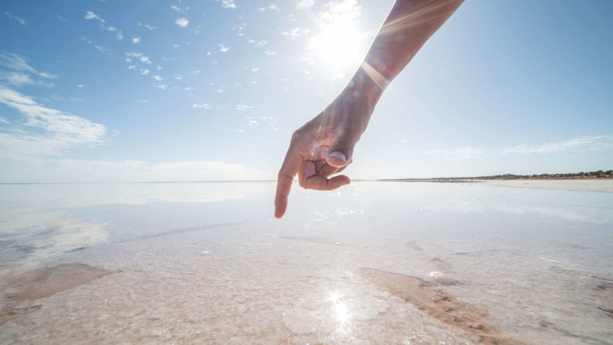 a hand points to a salt crust at a salt mining operation in australia.