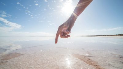 a hand points to a salt crust at a salt mining operation in australia.