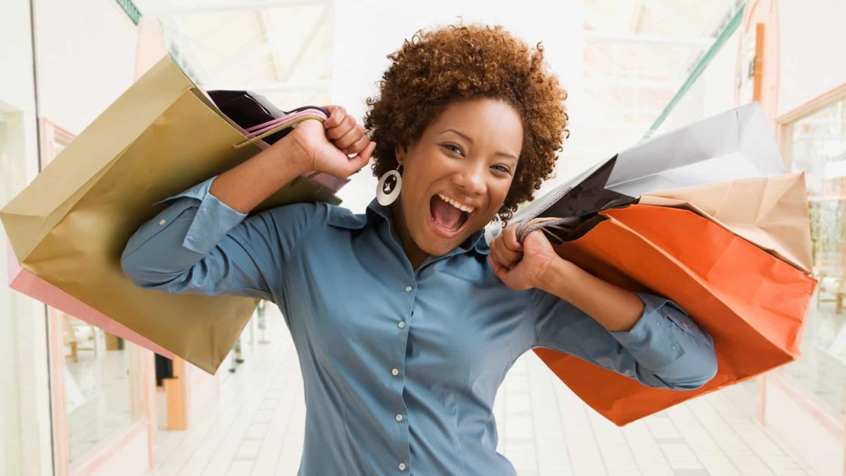 Afterpay share price a happy shopper with a wide mouthed smile holds multiple shopping bags up around her shoulders.