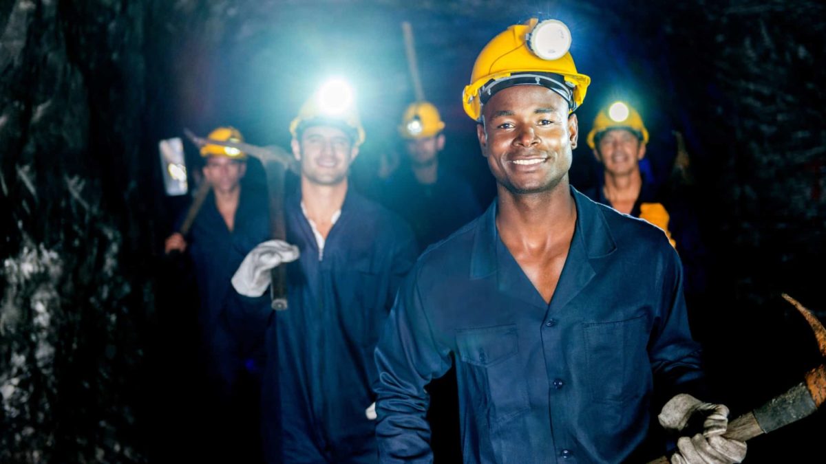 Miner team in the caves with their lights on and smiling