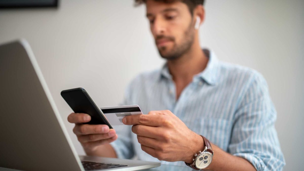A man makes an online payment with his laptop and credit card.