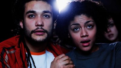 anxious couple hold hands while looking shocked at screen