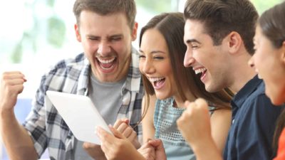 Four people gather around laptop and cheer