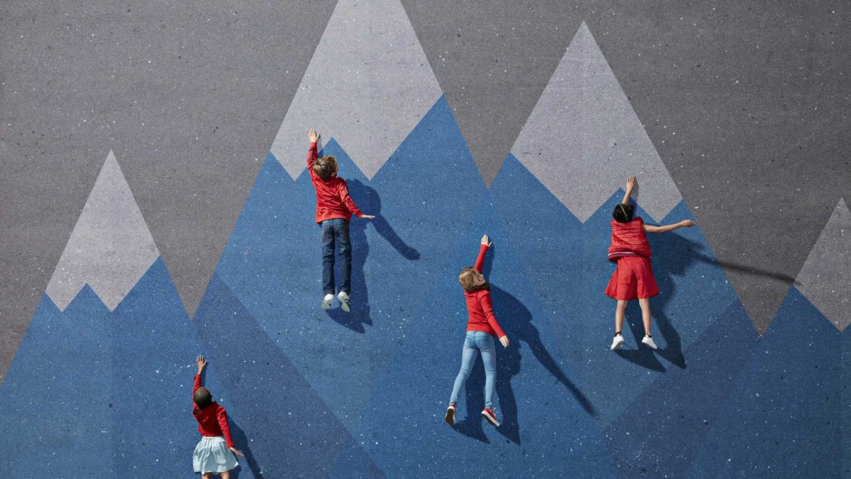 Four children climbing up a wall at different stages