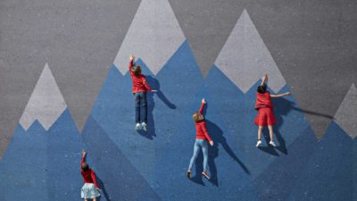 Four children climbing up a wall at different stages