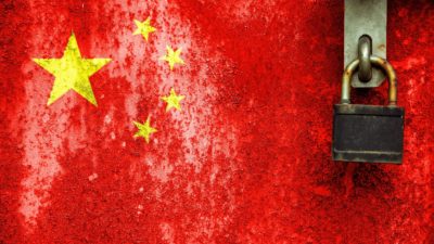 The yellow stars of China's flag painted on a red wall next to a padlock, indicating the risk of trading with China