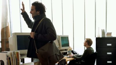 A man waves goodbye as he leaves an office.