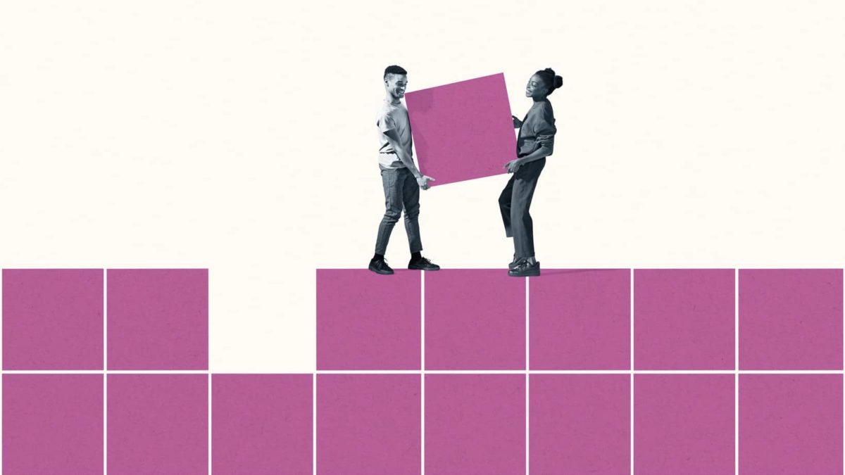 Two people carry a square shape to fit into a block of squares