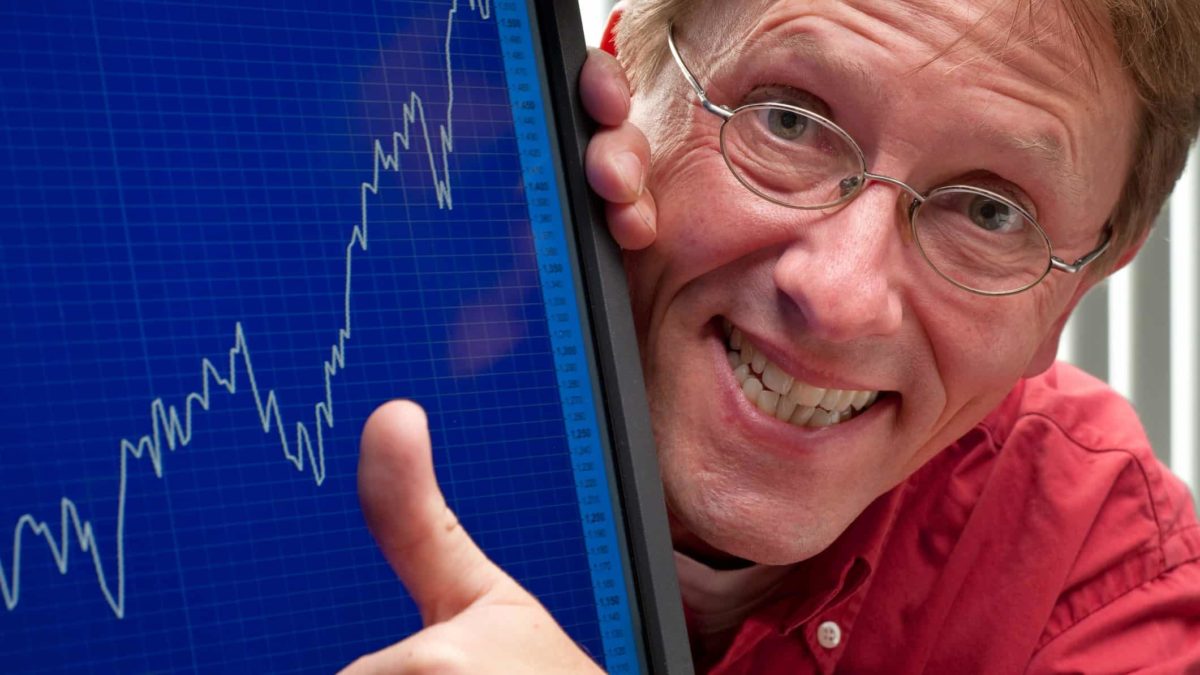 Man puts thumb up next to stock market graph
