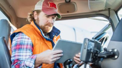 Truck driver sits in cab using laptop