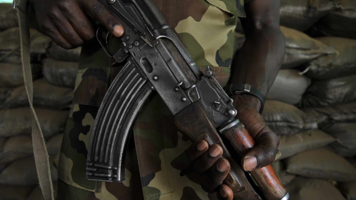 a close up image of a soldier holding an automatic weapon in his hands against the background of army fatigues.