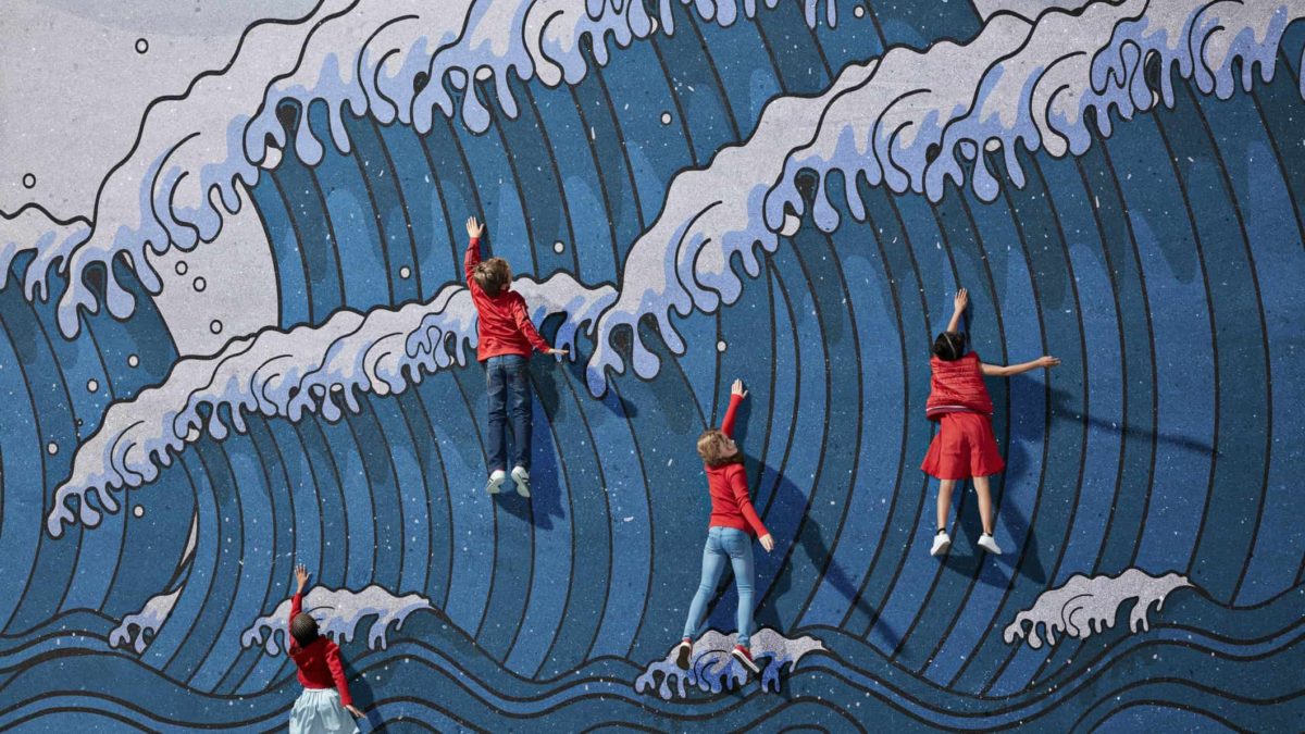 children wearing red clothing are featured on a wall painted with a large wave pattern. The children are standing but are making swimming gestures with their arms to look as though they're battling against the sea.