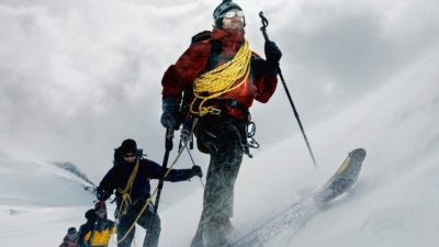a cross country skier leads three others up an incline amid cold and snowy conditions in a snowy mountain setting.