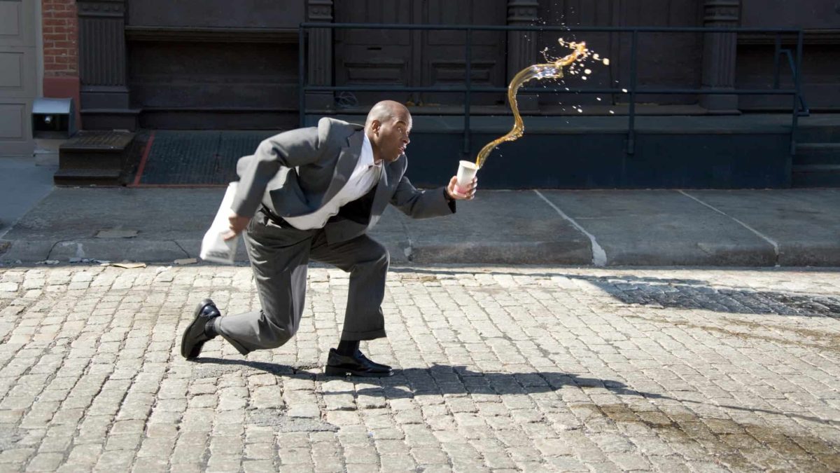 A businessman slips and spills his coffee.