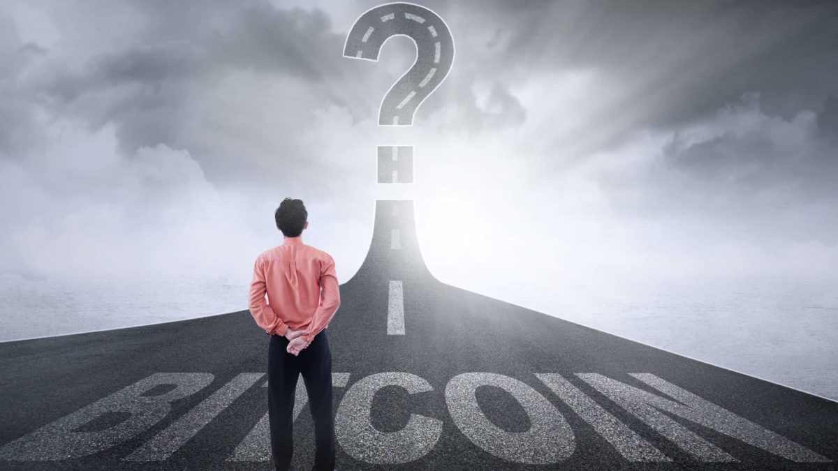 A man stands on a road marked Bitcoin with a questionmark ahead.