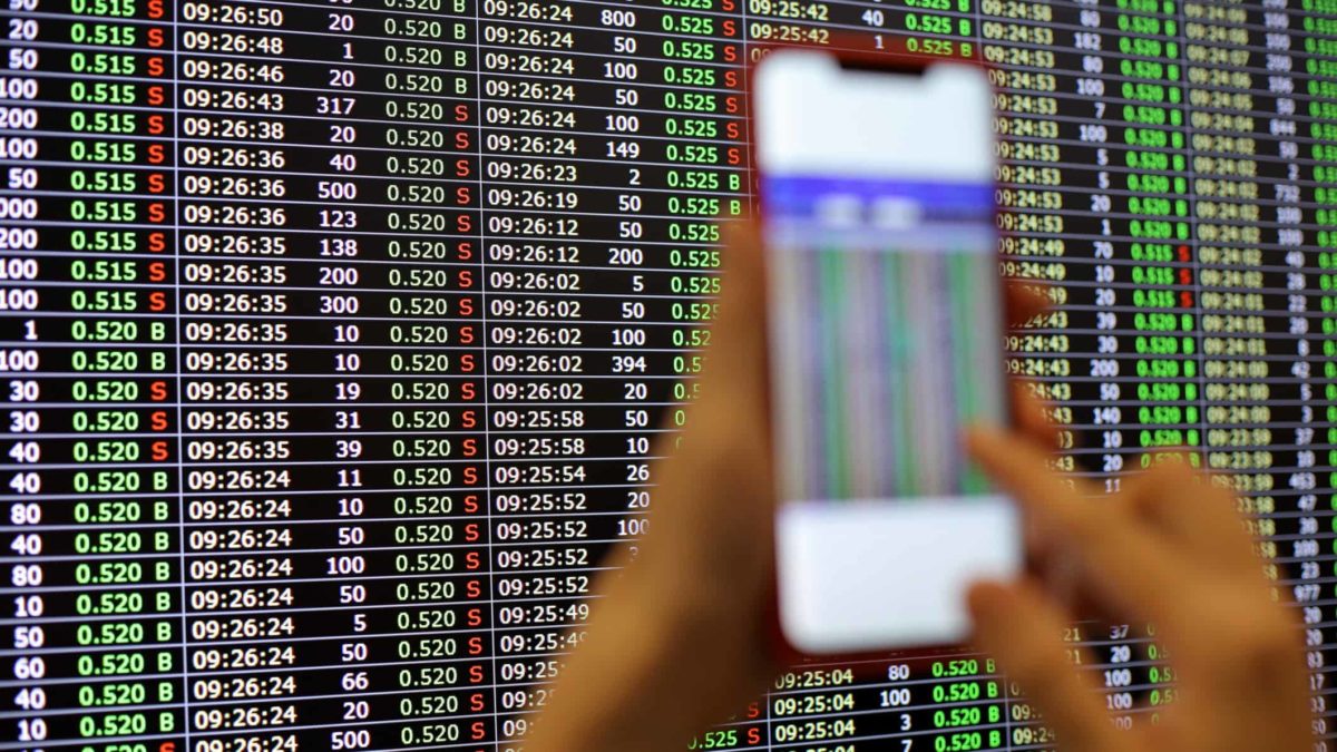 holding up phone in front of stock market