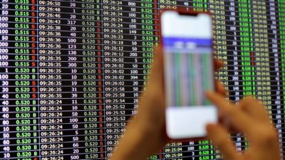 holding up phone in front of stock market