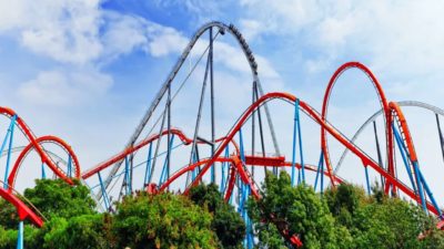A big red and blue rollercoaster circuit photographed from far away with the blue sky in the background.