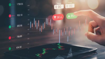 Concept image of a finger hovering in front of a buy and sell button in front og a stockmarket graphic.