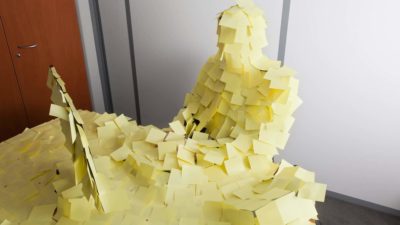 An office worker and his desk covered in yellow post-it notes