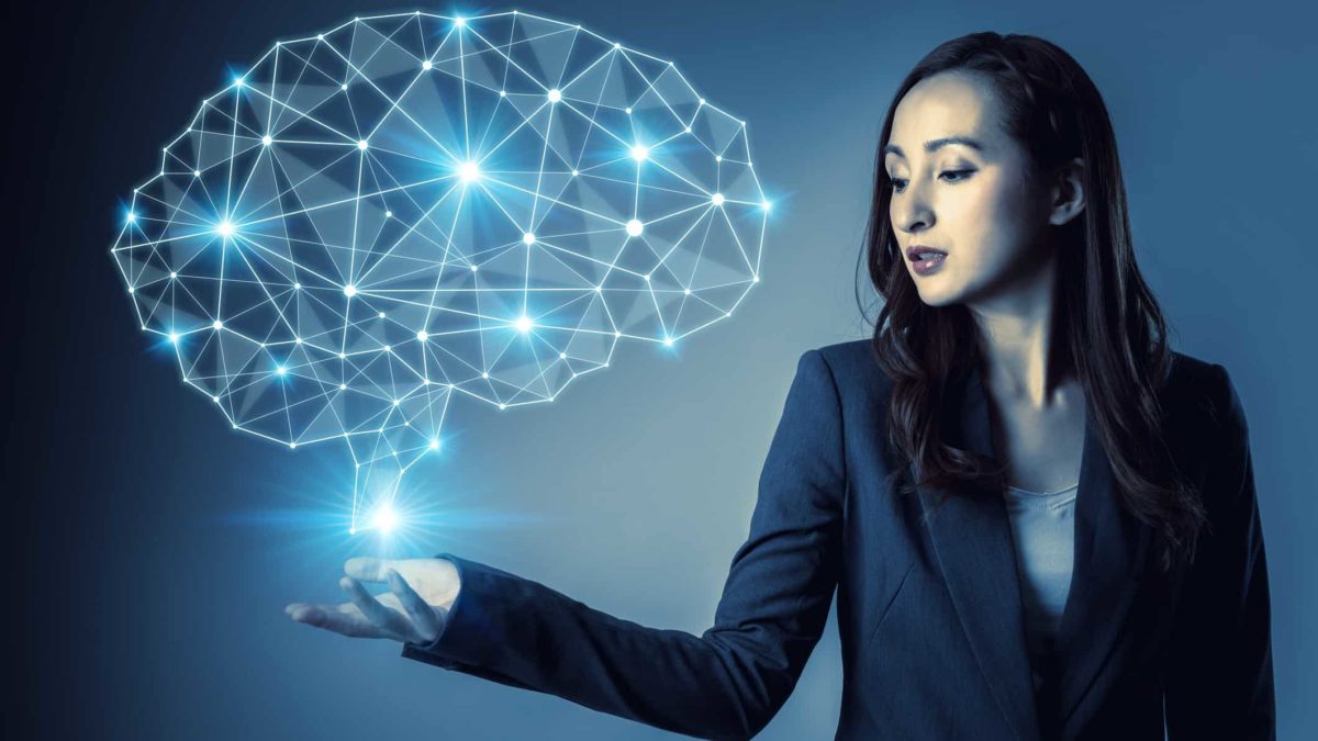 A woman holds her hand out under a graphic hologram image of a human brain with brightly lit segments and section points.