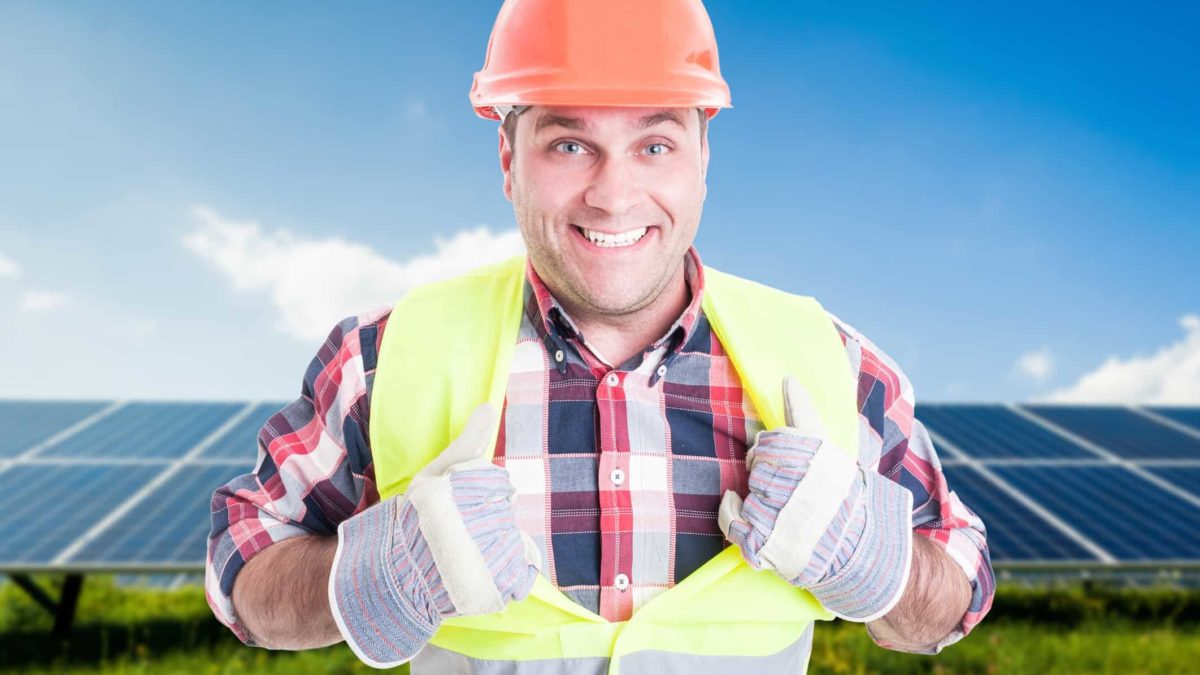 Thumbs up for clean energy. A construction worker or miner in front of solar panels.