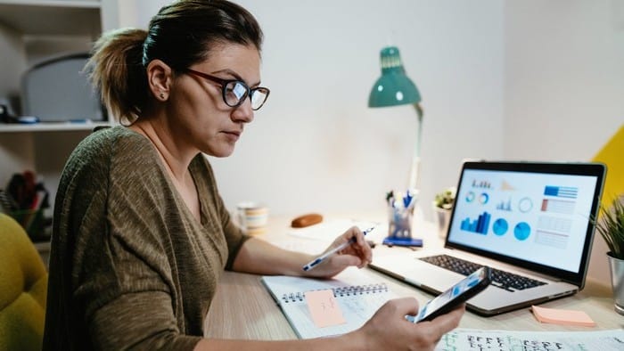 Woman looking at her smartphone and analysing share price.