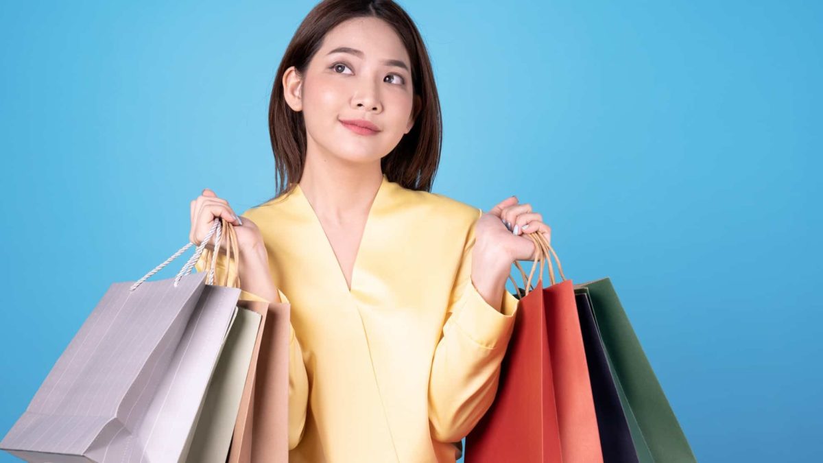 a woman with lots of shopping bags looks upwards towards the sky as if she is pondering something.
