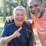 Two older male friends using tech to record their run.