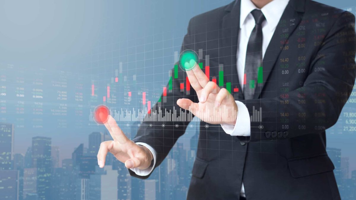 Man presses green buy button and red sell button on a graph.