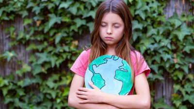 Worried girl holds model of planet loking sad.