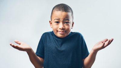 A boy shrugs his shoulders, he doesn't know what's going on.