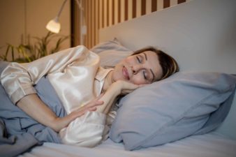 a mature woman sleeps peacefully in bed with a smile on her face as though she is very satisfied about something.