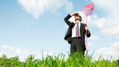 A businessman holding a butterfly net looks up trying toi catch a multi-bagger ASX share