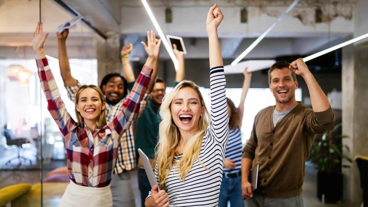 A group of office workers pump the air to celebrate